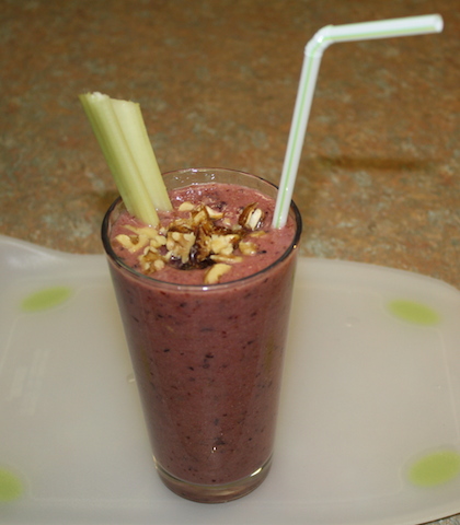 walnut topped smoothie with a piece of celery for dipping and munching and a straw for sipping that delicious berry colored smoothie