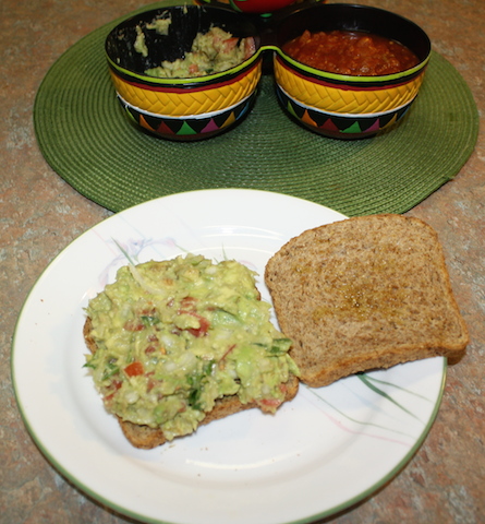 Two pieces of sprouted grain bread spread with colorful delicious guacamole