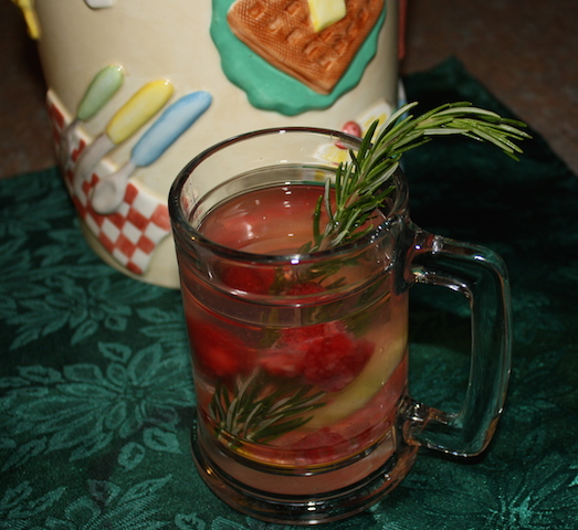 refreshing glass of fruit water with raspberries and lemon slices and a sprig of rosemary