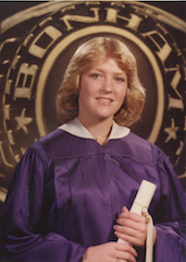 Judith's daughter, Jennifer, wearing a  graduation gown holding her diploma.
