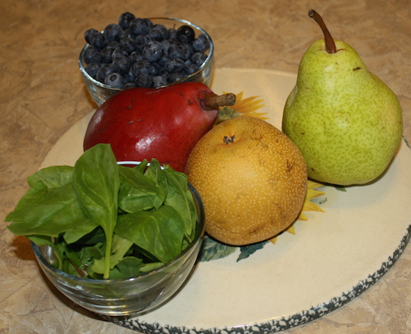 Three varieties of pears with some blueberries in a small bowl and some spinach