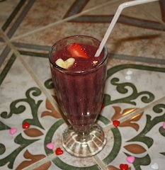 smoothie decorated with banana slice and strawberry which have been cut to resemble hearts