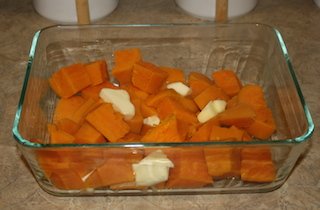 sweet potatoes in the baking pan with pats of butter on them