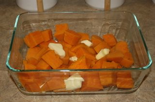 sweet potatoes in the baking pan with pats of butter on them