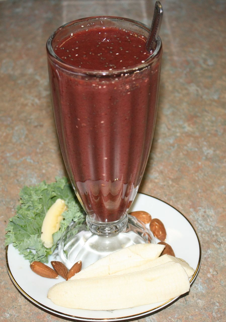 red smoothie on a plate garnished with bananas, almonds and kale for a healthy cholesterol lowering breakfast
