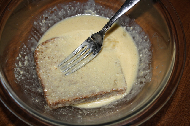 Using a fork to dip bread in wafflette batter.