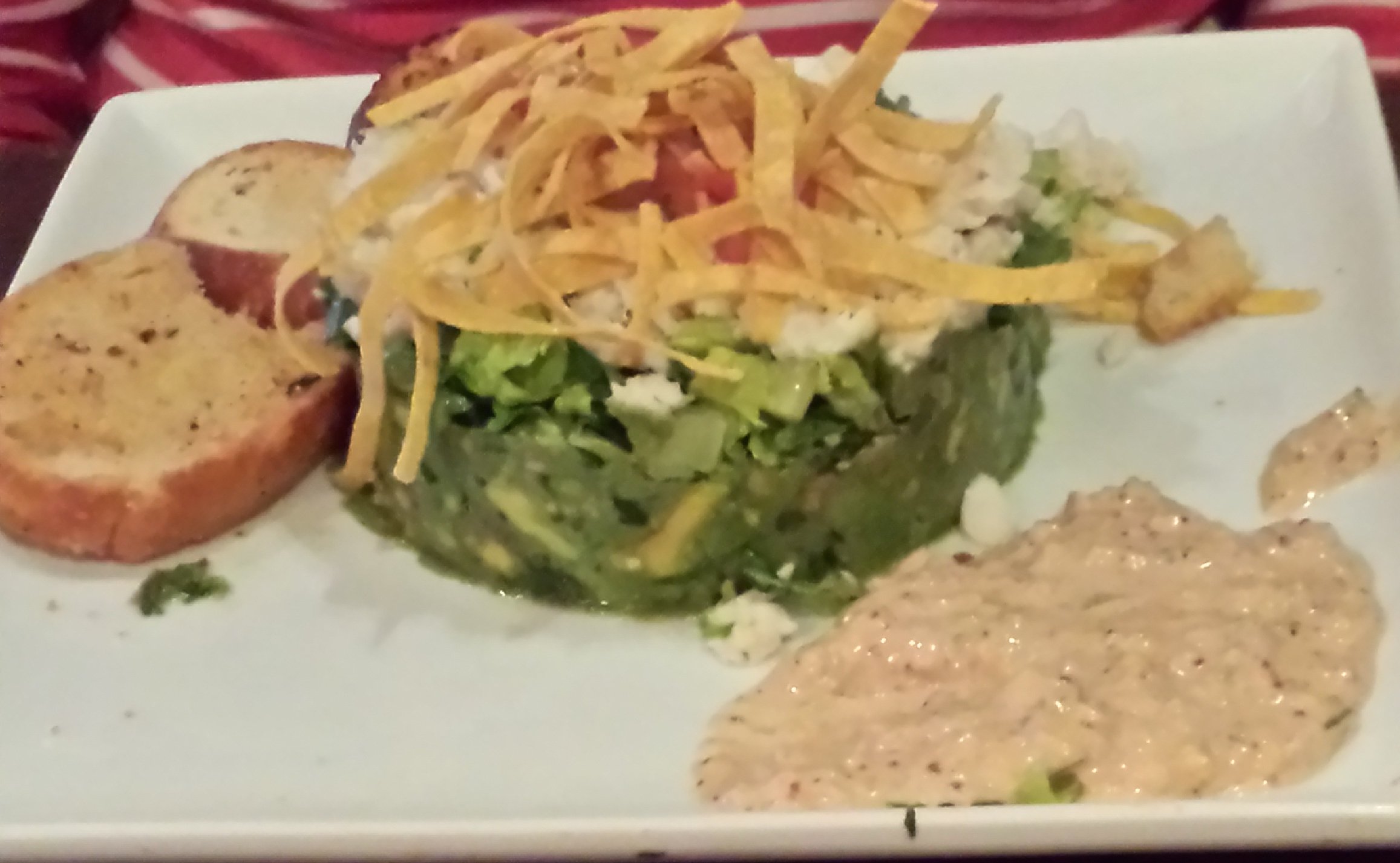 an avocado salad filled with romaine salad topped with crispy chips and plate garnished with tangy dressing