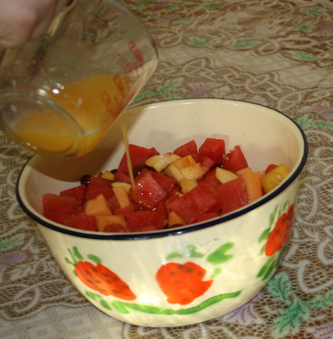 Pouring orange juice over salad
