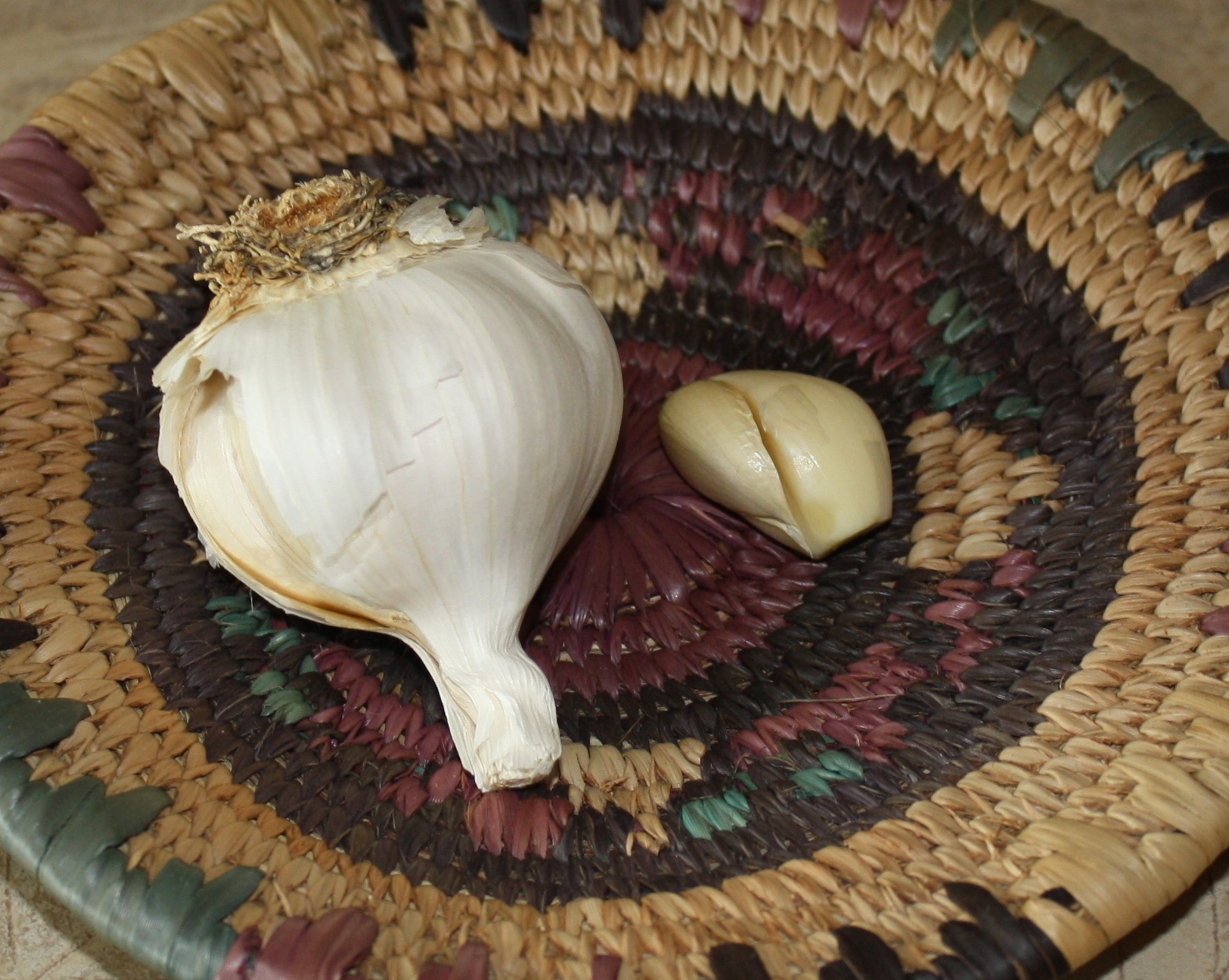 A basket containing a pod and clove of garlic. 4 cloves a day helps normalize cholesterol