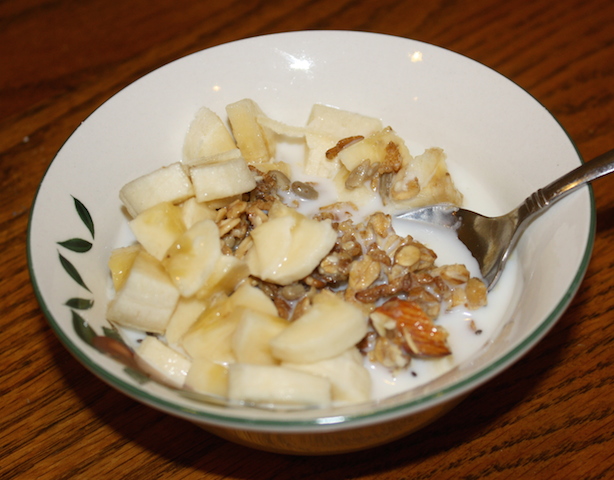 A nutritious toasty brown bowl of homemade granola topped with bananas and almonds