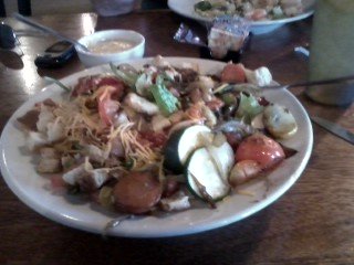 A variety of vegetables on a bed of salad greens. Includes zucchini, carrots, tomatoes and more. colorful and tasty