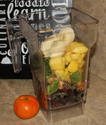 the blender container full of fresh fruits and spinach and almonds