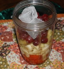 ingredients in the blender container. Fresh fruit topped with ice cubes ready to be whirred to the right consistency