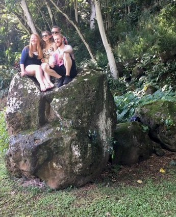 Young adults sitting on a tall rock