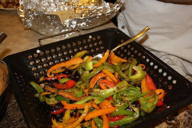 Red, yellow, green and orange peppers cooked in a basked on the barbecue