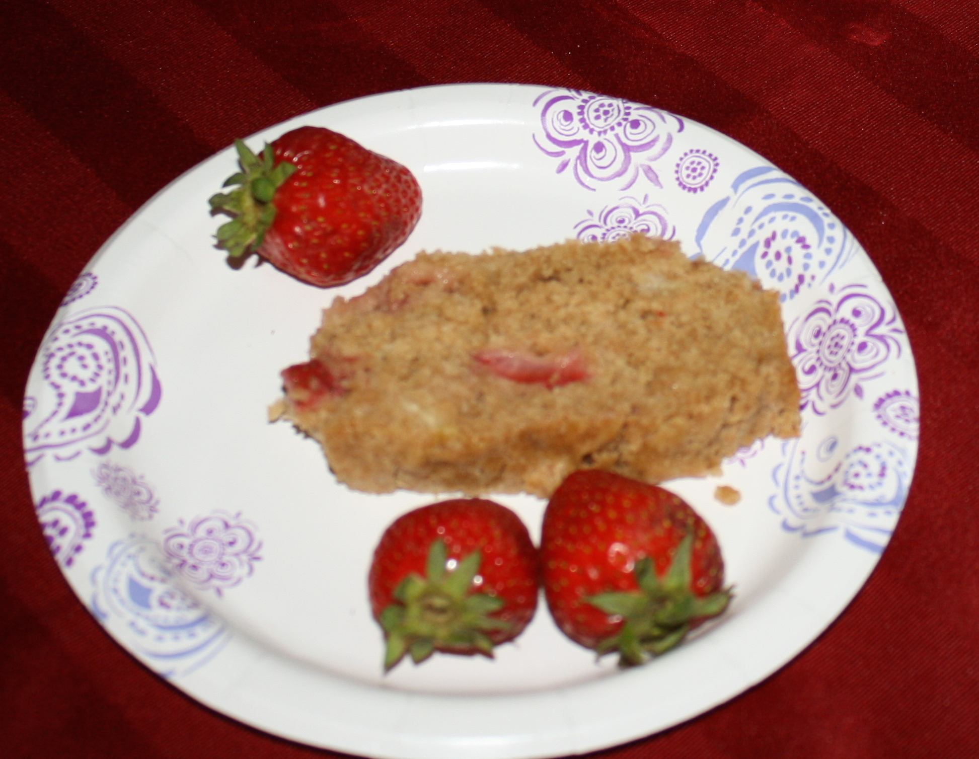 a slice of strawberry banana bread garnished with three fresh strawberries