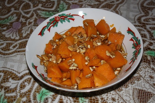 A tasty dish of sweet potatoes with pecans and maple syrup in a Christmas decorated bowl.